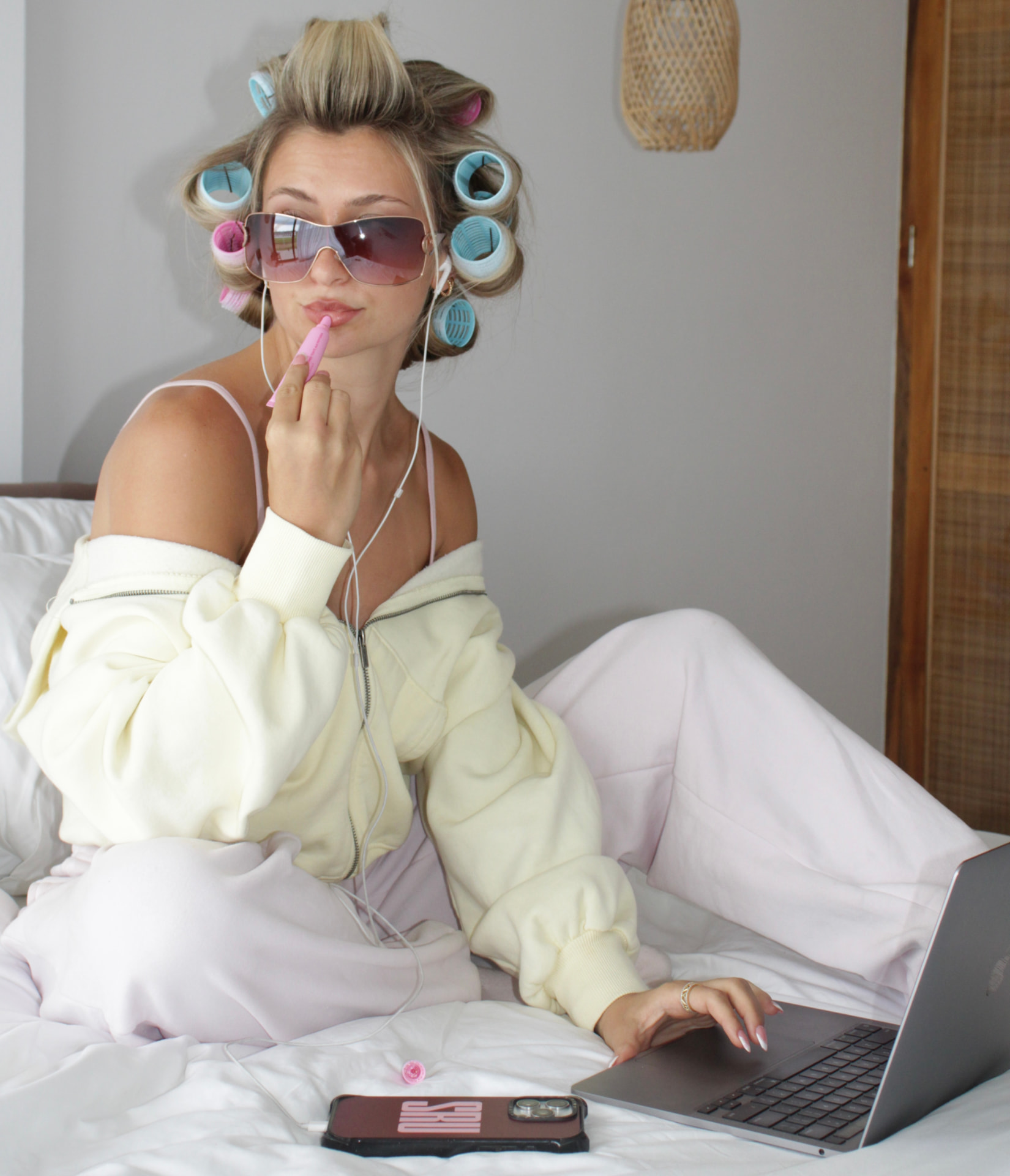 Starra in hair rollers and sunglasses working on her laptop in bed